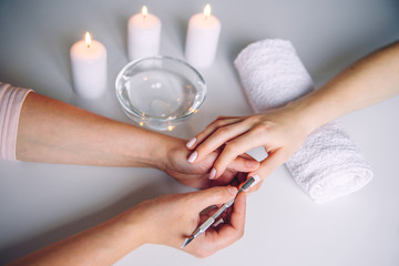 Nail care. Closeup of beautiful woman hands getting manicure in spa salon. Female manicurist...
