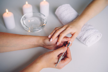 Nail care. Closeup of beautiful woman hands getting manicure in spa salon. Female manicurist...