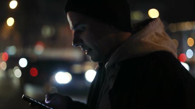 attractive man using smartphone telephone road traffic blurred background night city light bokeh connecting 3g application notification touching screen tapping pointing finger display businessman guy
