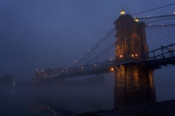cincinnati, ohio and covington kentucky riverfront and bridges in the fog on misty day at dusk