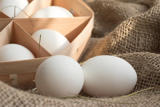 Close-up view of white chicken eggs in ecological packaging with hay or straw on sackcloth in a rustic style