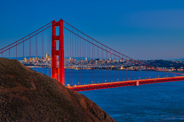 Golden Gate Bridge in the evening, with San Francisco Skyline seen through the cables of the bridge