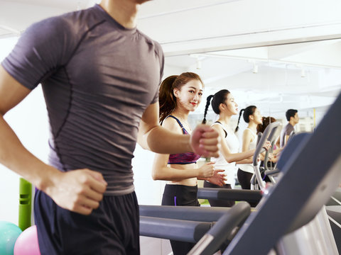 young asian people exercising on treadmill, focus on the girl in the middle