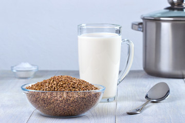 Glass bowl with buckwheat and milk for cooking buckwheat porridge.