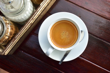 White coffee cups full of fresh espresso in sunshine light, top view on old wooden table