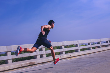 Fototapeta na wymiar Man running sprinting on road. Fit male fitness runner during outdoor workout.