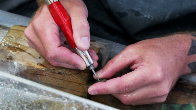 a man carves a piece of jade in a factory at hokitika, new zealand