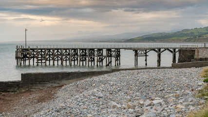 Damaged pier, the pebble beach and the sea in Trefor, Gwynedd, Wales, UK