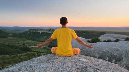 Man in lotos pose on mountain. Yoga scene.