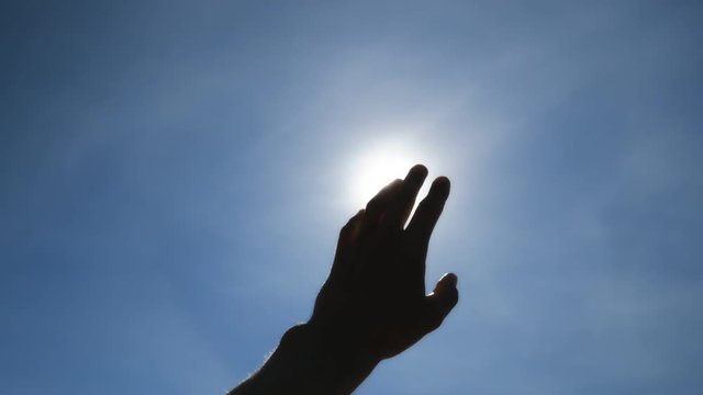 Hand of man strive to sun and deep blue sky. Conceptual scene.