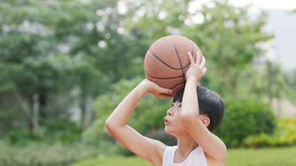 teenage Asian boy playing basketball outdoors preparing for shooting - Powered by Adobe