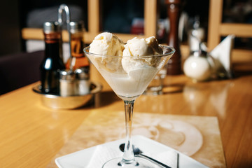Balls of filling ice cream in a martini glass and Cointreau liqueur, on a table in a restaurant.