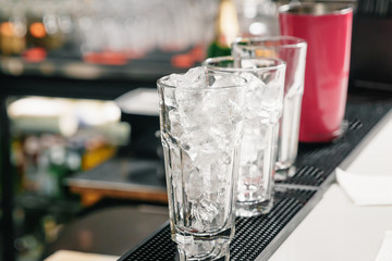 Empty, tall glasses of ice on the bar. Cocktail preparation, shaker.
