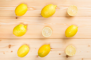 wooden light background with yellow lemons, and juicy halves on it