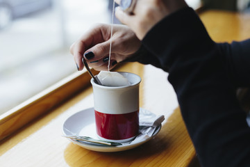 Girl sitting at cafe and stirring tea