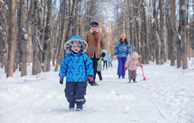 Kid playing in a winter park and have fun with family