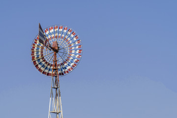 Wind turbine of red, white, blue color and old with blue sky.