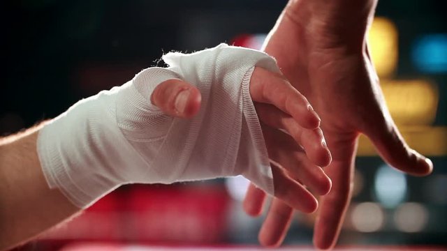 Close up boxing trainer or manager wrapping hands of a boxer reparing for boxing match
