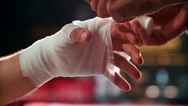 Close up boxing trainer or manager wrapping hands of a boxer reparing for boxing match