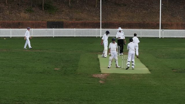 wide shot of two teams competing in a game of cricket