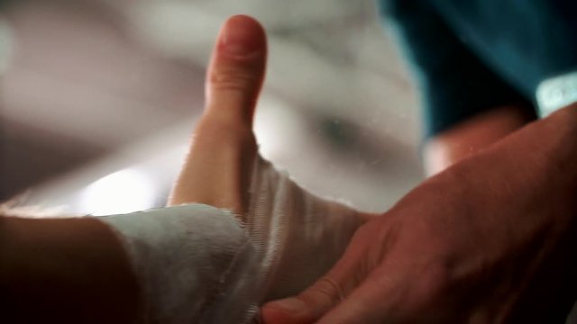 Close up boxing trainer or manager wrapping hands of a boxer reparing for boxing match