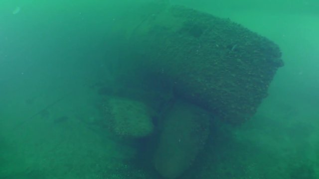The aft part of a sunken submarine: the camera approaches the rudders of depth and screws.
