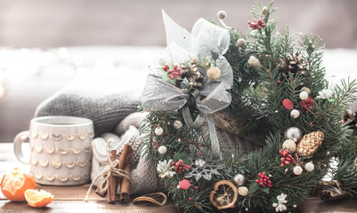 Christmas still life of trees and decorations, festive wreath on a background of knitted clothes and beautiful cups
