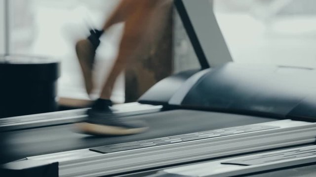 Male legs running on a treadmill in gym
