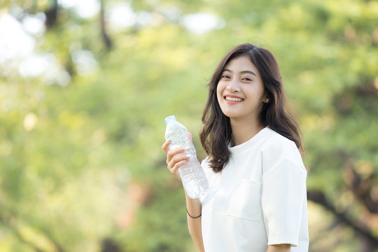 Attractive Asian Woman drinking water at garden. Woman with health care concept.