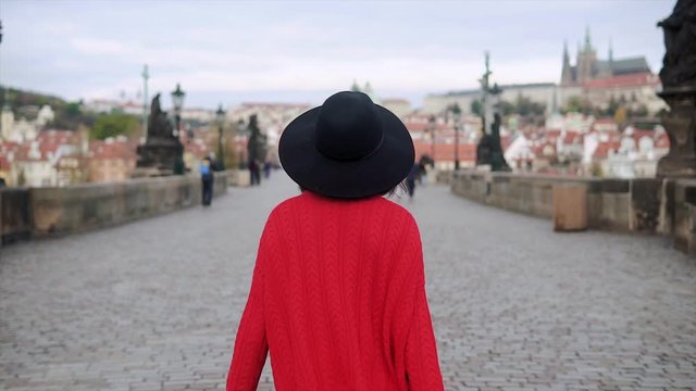 A young lady wearing hat walking in Prague