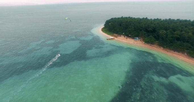 Aerial view of Kitesurfer cruising on empty blue water lagoon on tropical island