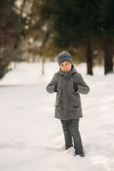 Fototapeta na wymiar A little boy walks in the park in the winter weather, play snowballs and rejoiced. Waiting for Christmas mood