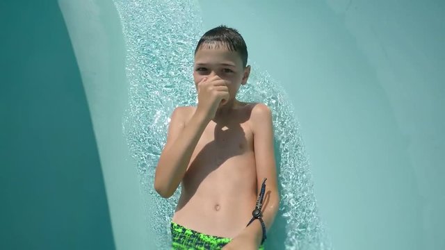 An impressive view of a happy boy sliding down in an aquapark and making a selfie in Turkey on a sunny day in summer. 