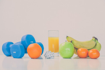 The concept of a healthy diet. Small dumbbells. Orange juice. Bananas. Oranges. Apples. Measuring tape waist. On a white background. healthy lifestyle. sport. Fitness food