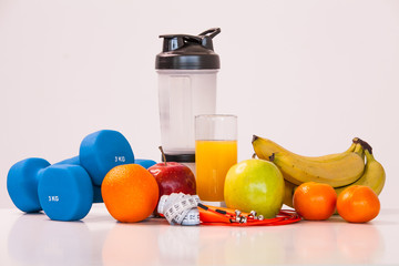 The concept of a healthy diet. Small dumbbells. Shaker. Bananas. Apples. Oranges. The skipping rope. Measuring tape waist. on a white background. healthy lifestyle. sport. Fitness food.