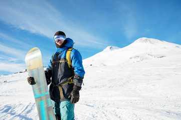 A professional snowboarder stands with his snowboard