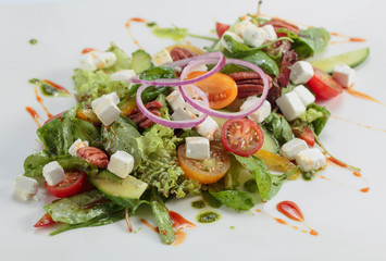 Green salad with cheese , nuts and pesto.