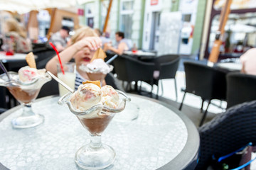Sweet little girl with glasses is eating ice cream at restaurant, pastry shop