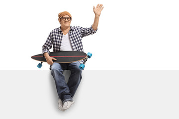 Old hipster with a longboard sitting on a panel and waving
