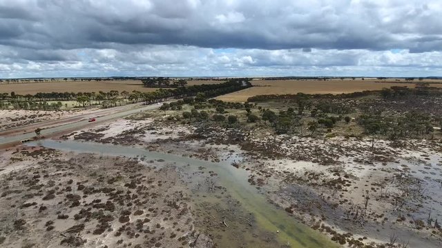 Luftaufnahme während des Flug einer Drohne im Outback von West-Australien mit überschwemmtem Teilgebiet in Richtung eines Highway