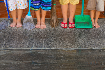 Many boys legs with cleaning supplies, broom, mob, dustpan