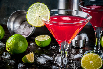 Red cosmopolitan cocktail with lime in martini glass, on dark rusty background copy space
