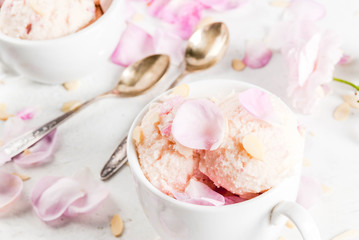 Summer refreshing desserts. Vegan diet food. Ice cream with rose petals and slices of almond, in white serving bowls, on a white concrete table. Copy space close view