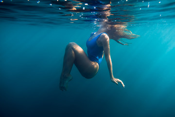 Obraz na płótnie Canvas Underwater woman portrait in blue ocean with day light.