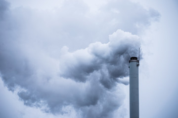 Industrial long  chimney with dark smoke going outside.