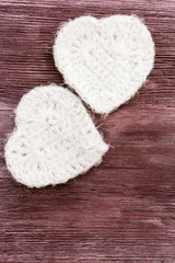 Two white hearts on old wooden background. Knitted white heart. Composition for Valentine's day or postcards. Background for congratulations with copy space. Vertical format.