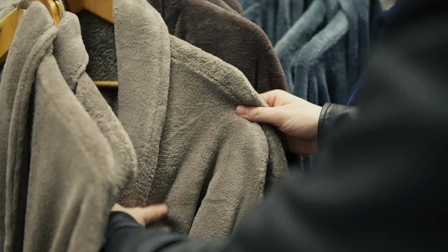 Closeup view of man's hands choosing a bathrobe in the store of bed linen and accessories