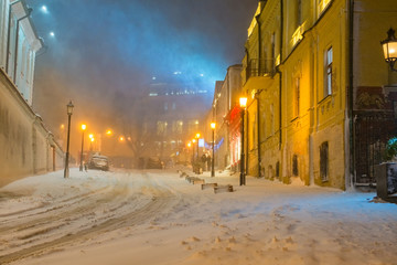Evening in the night snowy street under snowfall
