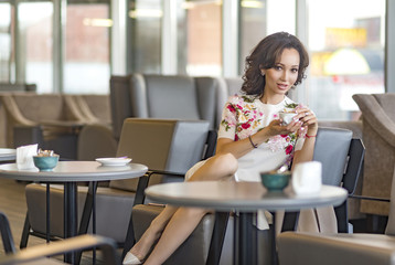 Beautiful happy pretty young woman sitting in a cafe.