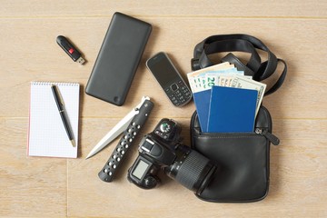 Spy kit.  Notepad with pen, USB flash drive, power bank, phone, pocket knife, camera and a man purse with passports and money of different currencies. 
